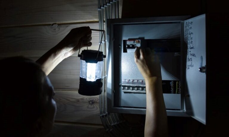 Man with portable light switching on breaker