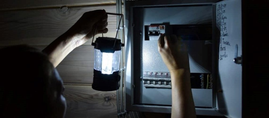 Man with portable light switching on breaker