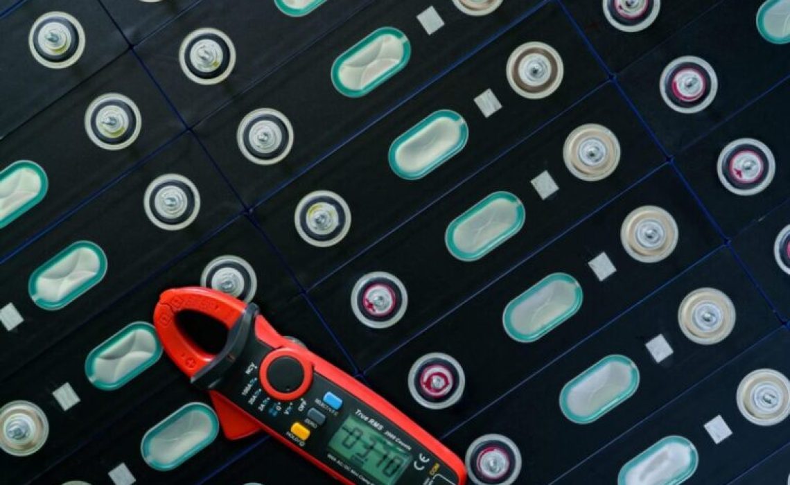 Electric vehicle lithium NMC battery with multimeter. Electric car battery manufacturing factory. Lithium-ion cell. Lithium NMC rechargeable battery. EV car energy storage. Automotive battery cell.